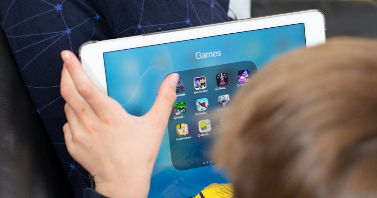 Gyerek egy kanap&eacute;n a tablettel a kez&eacute;ben